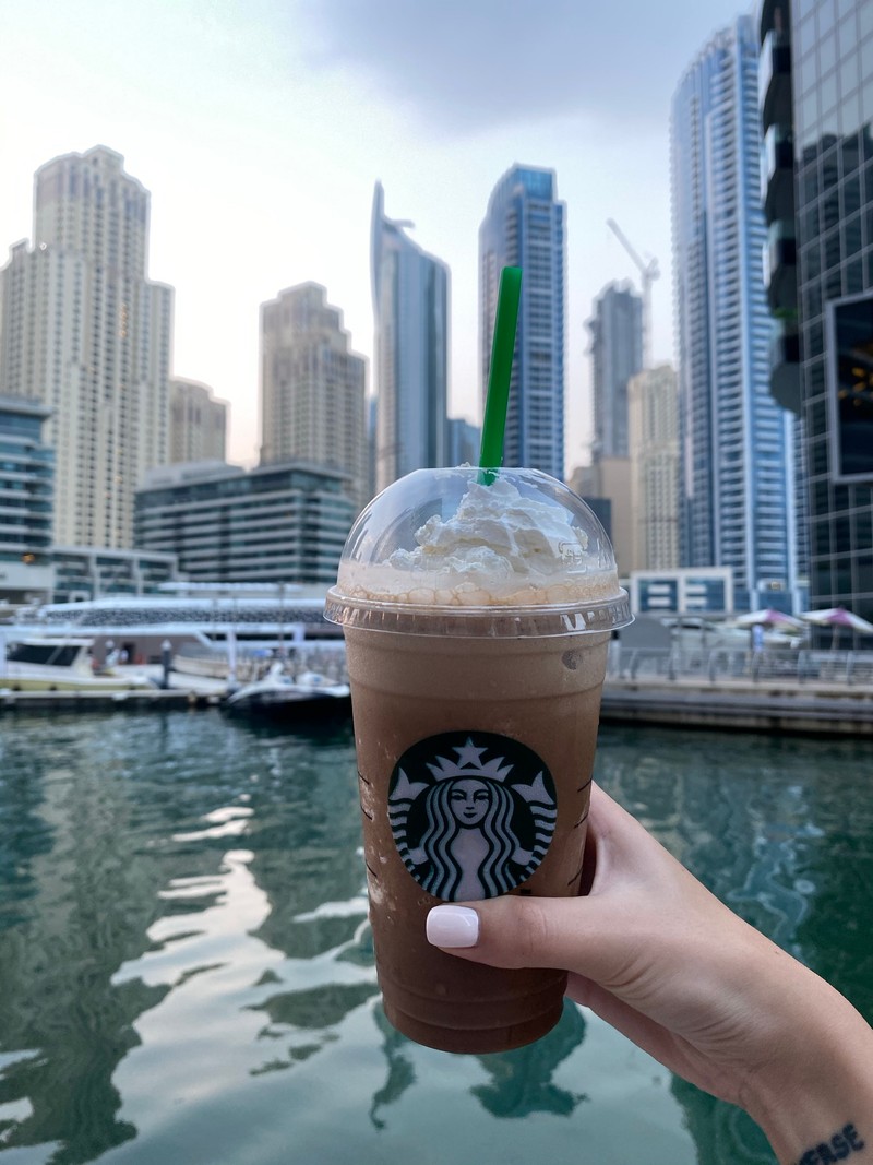 Кофе starbucks в пластиковом стакане с зеленой трубочкой перед силуэтом города (дубай, dubai, вода, башенный блок, жидкость)