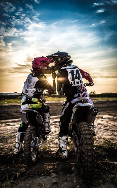 Unzertrennliche Bindung: Freestyle-Motocross-Fahrer teilen einen Moment bei Sonnenuntergang