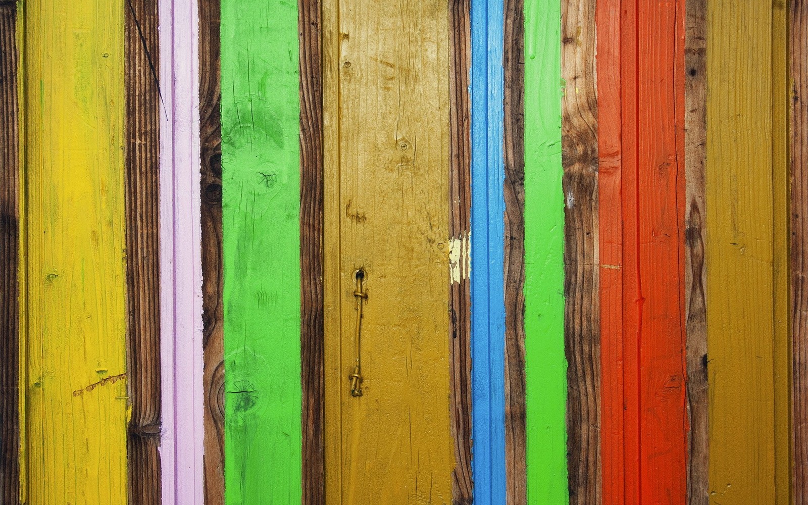 A close up of a colorful wooden fence with a fire hydrant (texture, green, yellow, wood stain, line)