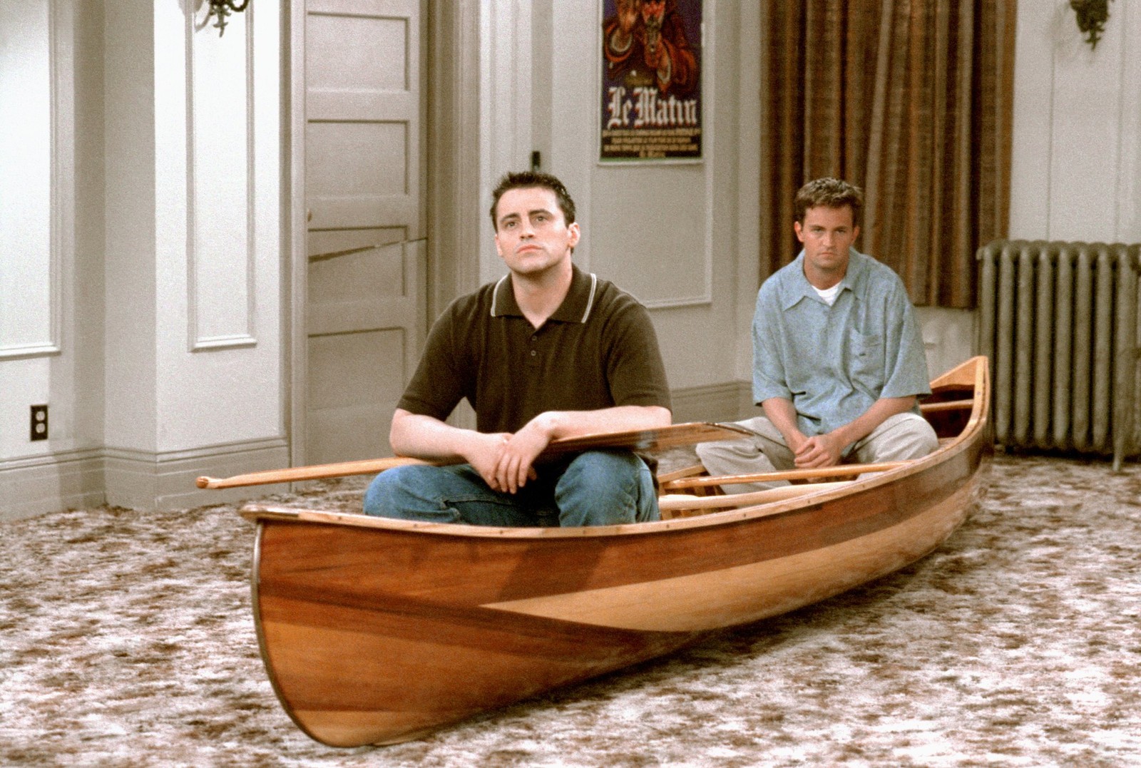 Il y a deux hommes assis dans un bateau sur le sol (joey tribbiani, amis, chandler bing, ross geller, monica geller)