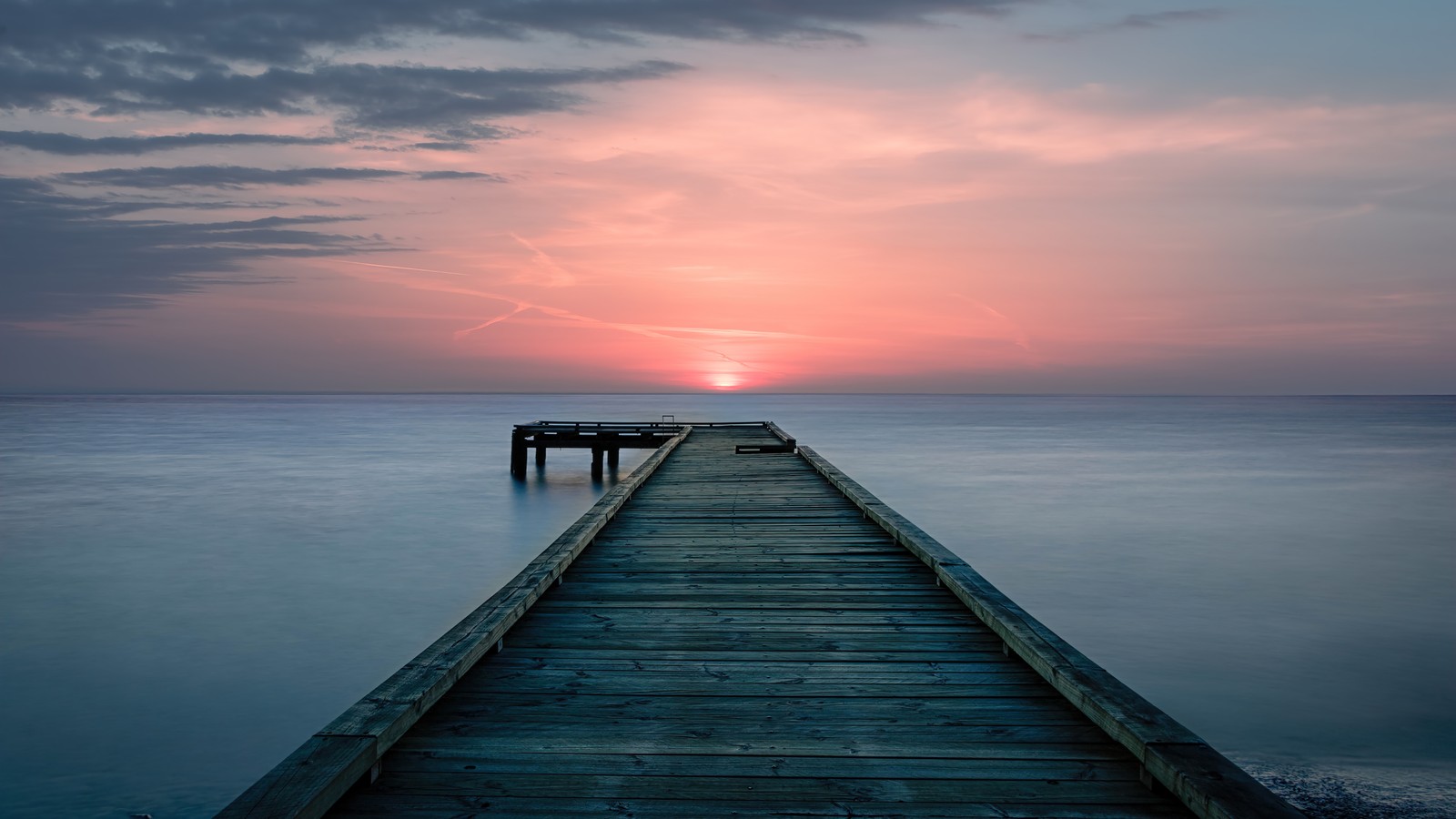 Quai arafed au coucher du soleil avec un ciel rose et des nuages (coucher de soleil, mer, quai, jetée, paysage)