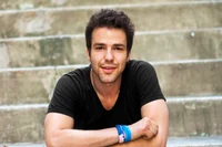 Young man with facial hair and headphones, smiling confidently on steps