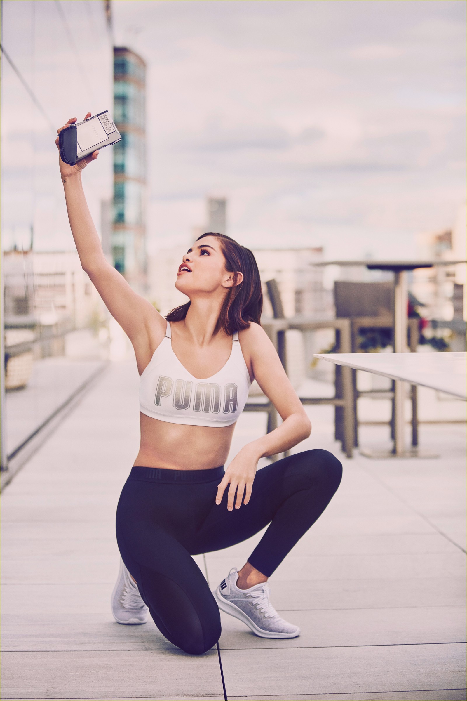 Una mujer árabe en un sujetador deportivo tomando un selfie con su teléfono celular (selena gomez, campaña de puma, sesión de fotos, 5k, gente)