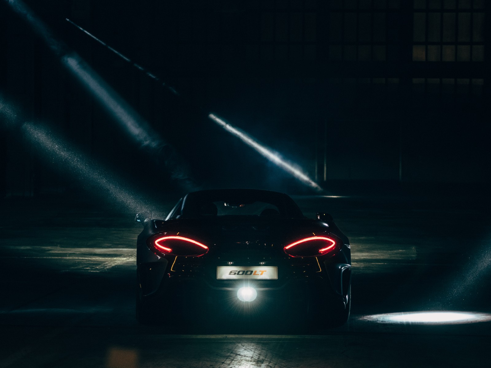 Un primer plano de un coche en un aparcamiento oscuro con luz proveniente de atrás (coche deportivo, mclaren automotive, coche, mclaren, supercoche)