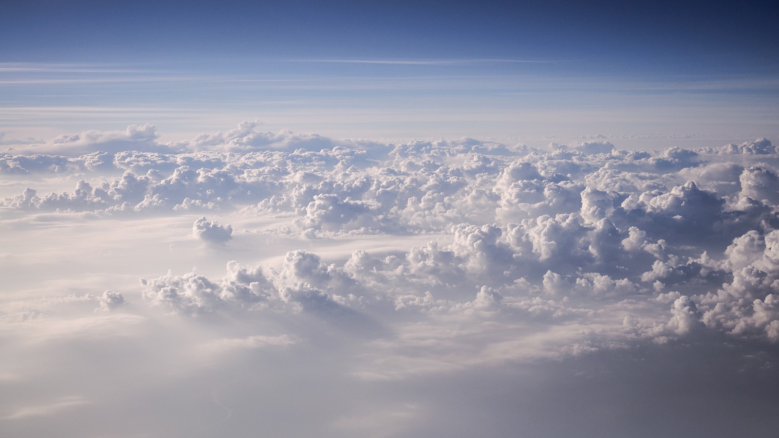 Vue aérienne d'un ciel rempli de nuages avec un avion volant au-dessus (nuage, journée, atmosphère, cumulus, horizon)