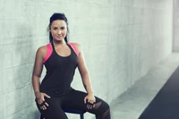 Demi Lovato con ropa deportiva, mostrando confianza y fuerza contra un fondo minimalista.