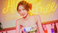 Tzuyu from TWICE radiates charm in front of a vibrant "Alcohol Free" neon sign, embodying the essence of the "Taste of Love" album.