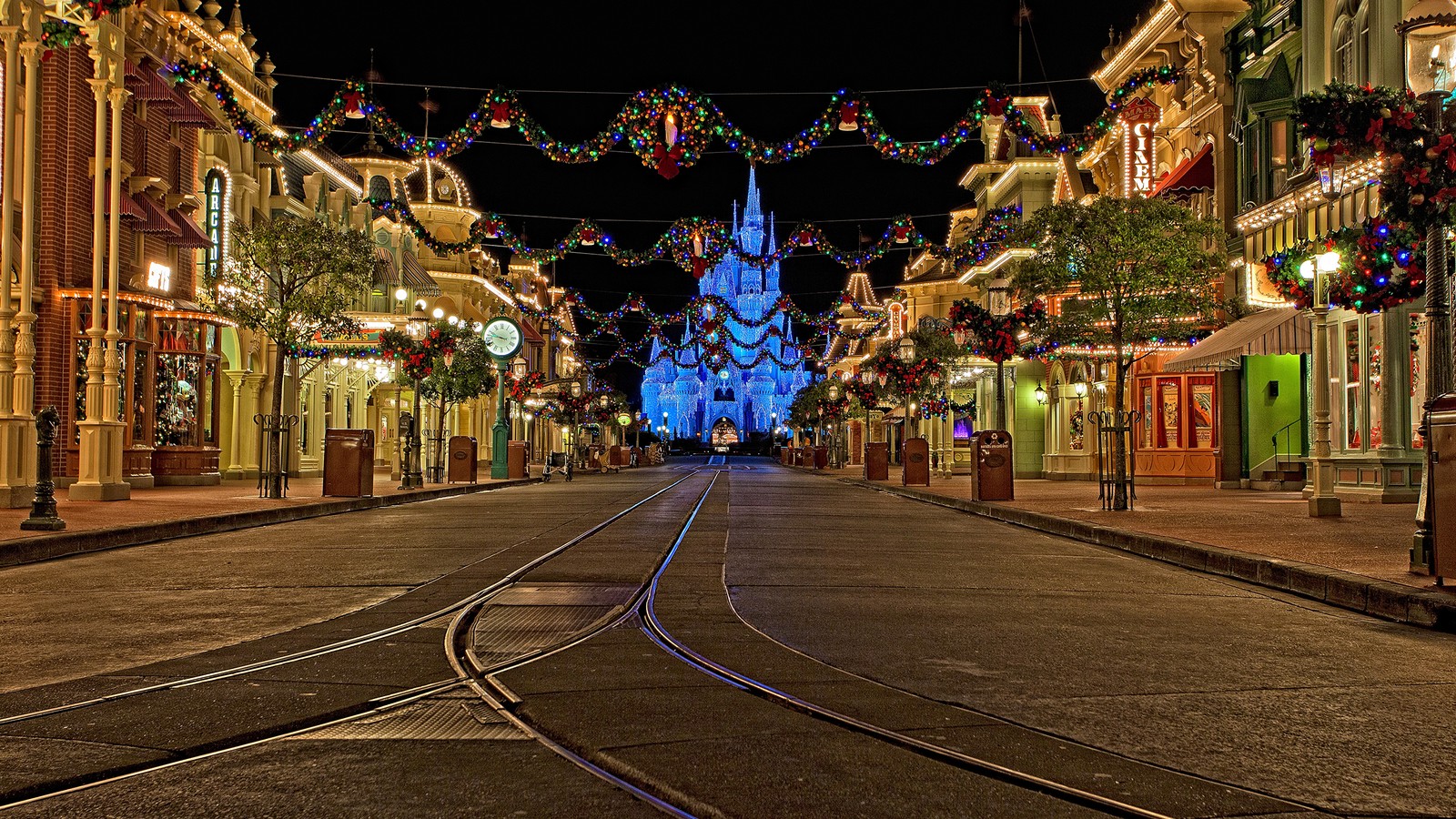 Arafed view of a street with a train track and a castle in the background (cinderella castle, the walt disney company, night, christmas lights, light)