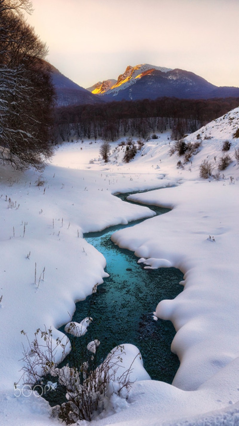 Snowy stream in a field with mountains in the background (landscape, snow)