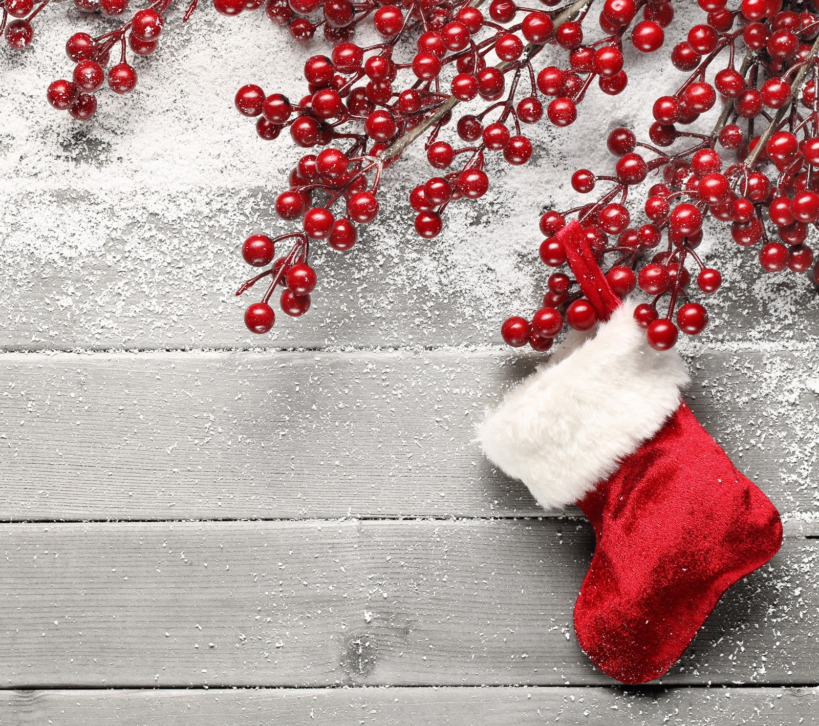 There is a red stocking with a white hat and red berries (christmas, decor, holiday, red)