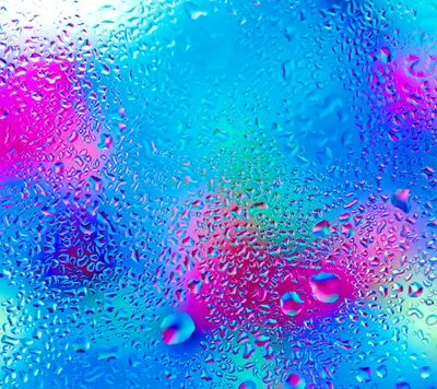 Gouttes d'eau colorées sur du verre avec un arrière-plan vibrant