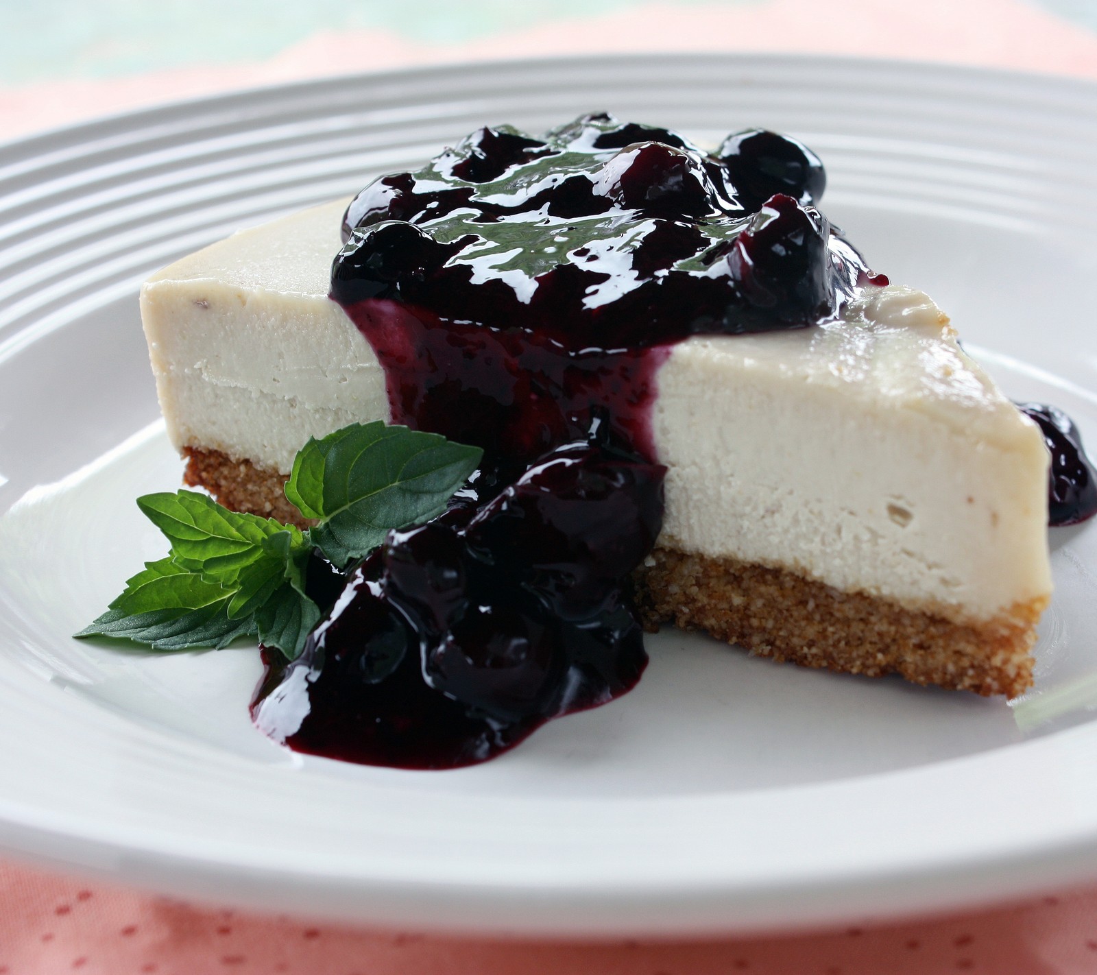 Un trozo de cheesecake con salsa de arándano en un plato (pastel, chocolate, uva, hq)