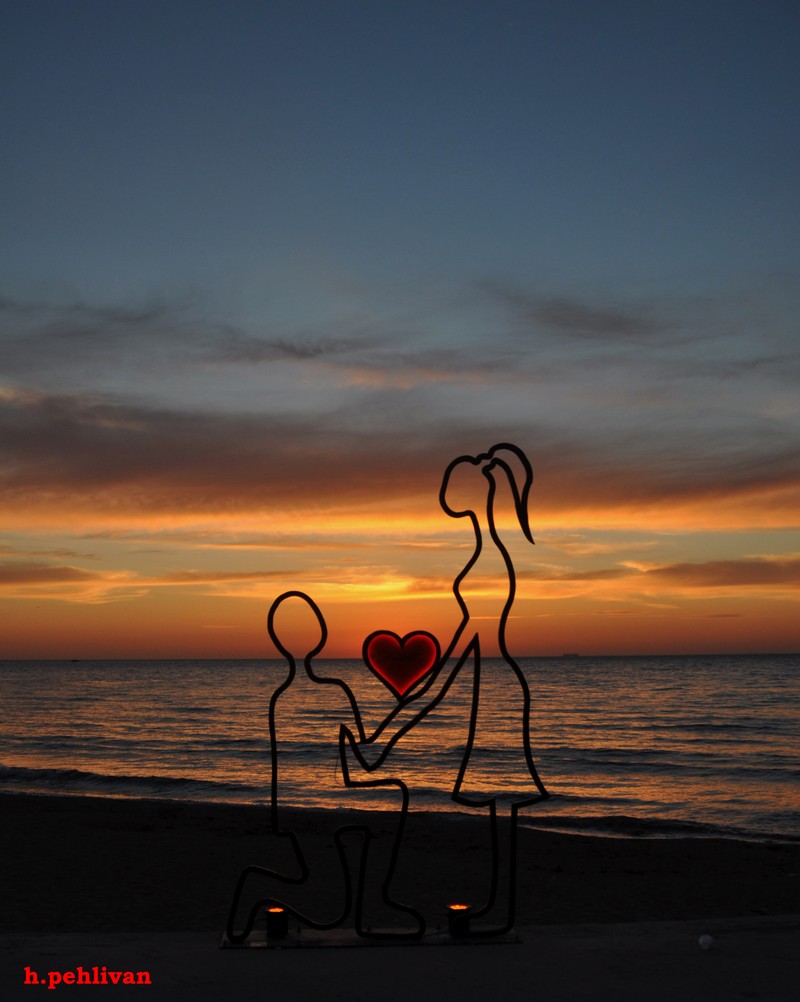 Escultura metálica árabe de um homem e uma mulher segurando um coração ao pôr do sol (céu, estrelas, yalova)