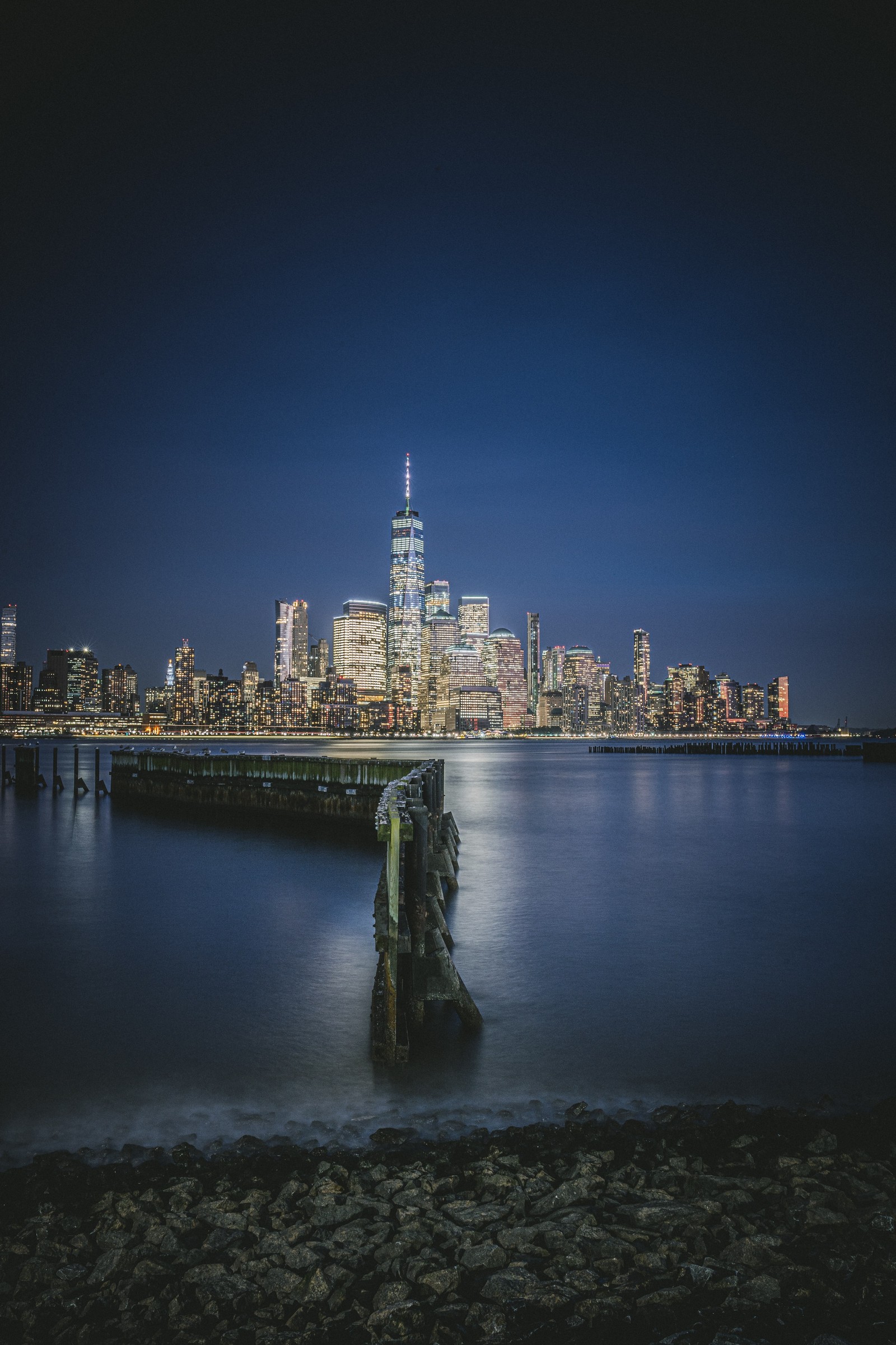 Vista aérea de um horizonte urbano à noite com um píer (hudson river waterfront walkway, jersey city, paisagem urbana, noite, luzes da cidade)