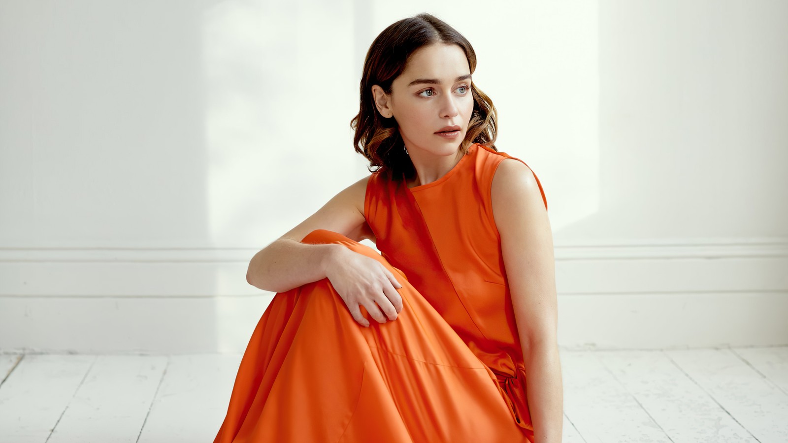 Une femme arabe en robe orange assise sur le sol (emilia clarke, séance photo, actrice, femmes, filles)