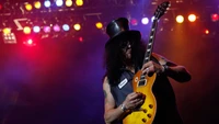 Guitarist with iconic top hat performing passionately on stage, embodying the essence of hard rock.