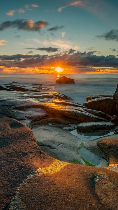 Coucher de soleil sur la côte rocheuse : Une réflexion au crépuscule