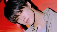 Jeno de NCT Dream dégage du charisme sur un fond rouge vibrant, affichant un look stylé qui reflète son essence K-pop.