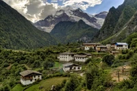 Malerisches Bergdorf, eingebettet in ein üppiges Tal, umgeben von majestätischen Gipfeln und lebendiger Grünfläche.