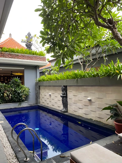 Piscina azul Majorelle rodeada de exuberante vegetación en un patio residencial