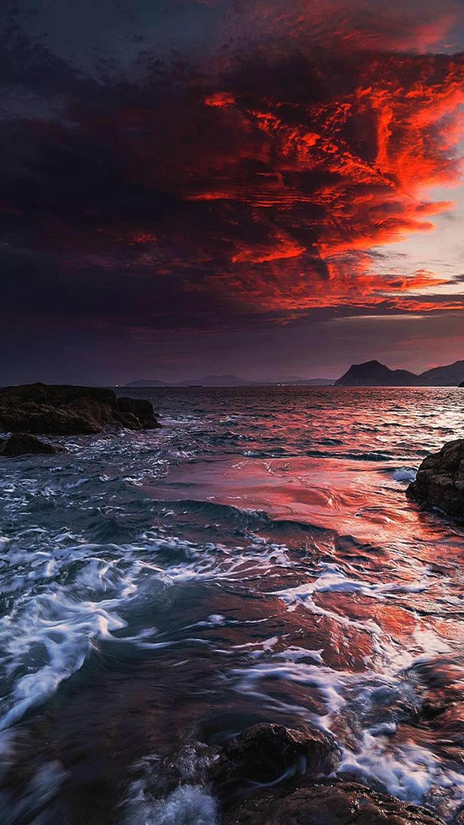 Pôr do sol sobre o oceano com ondas quebrando em frente a uma costa rochosa (hd, céu)