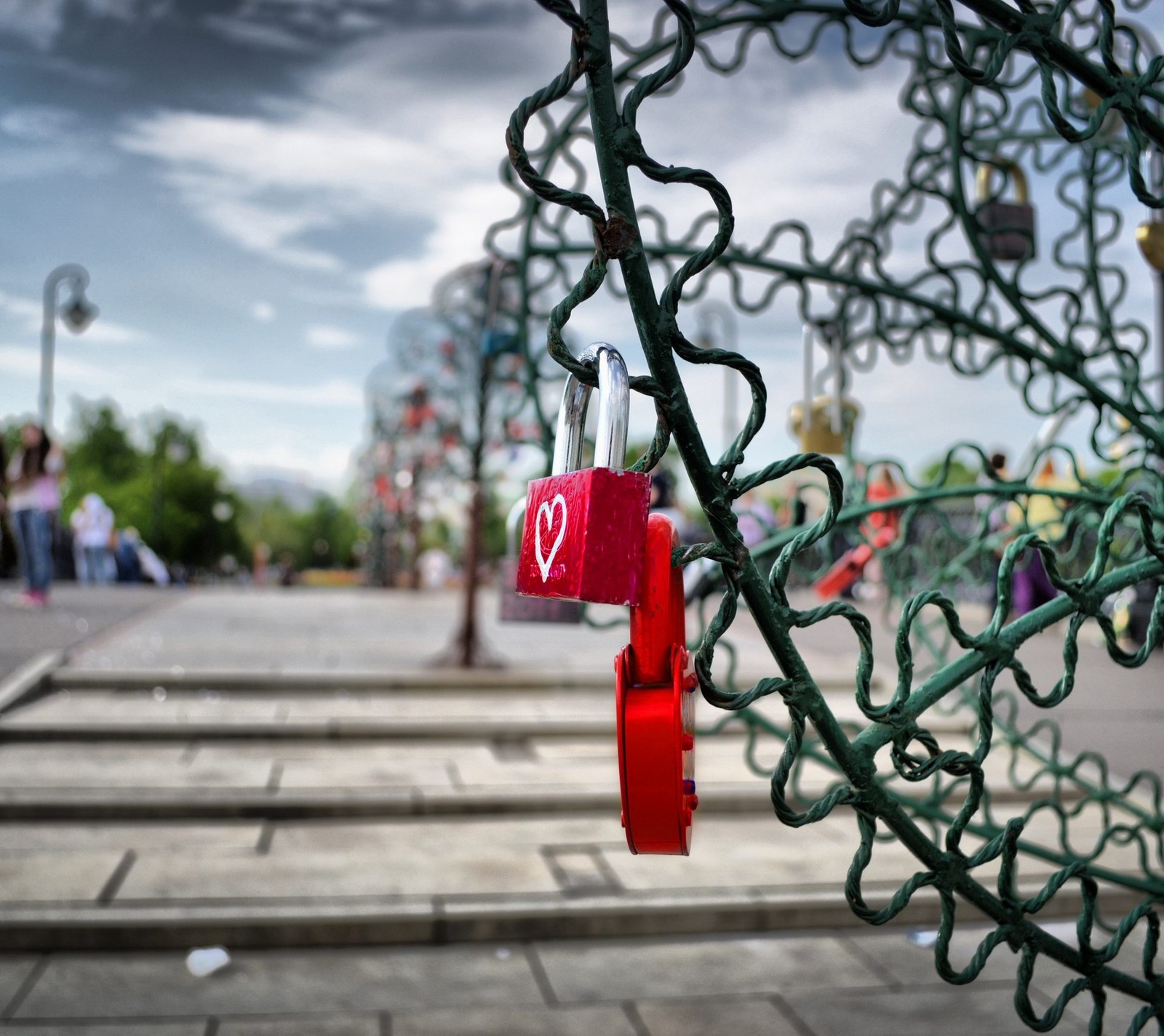 Há um cadeado vermelho em uma cerca verde com um coração nela (abstrato, amor, rua)