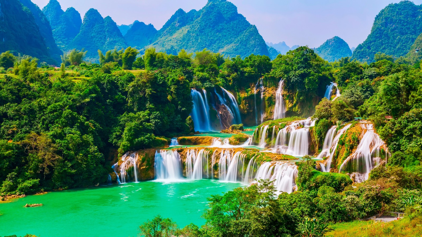 Una cascada en las montañas con agua verde (naturaleza, cascadas)