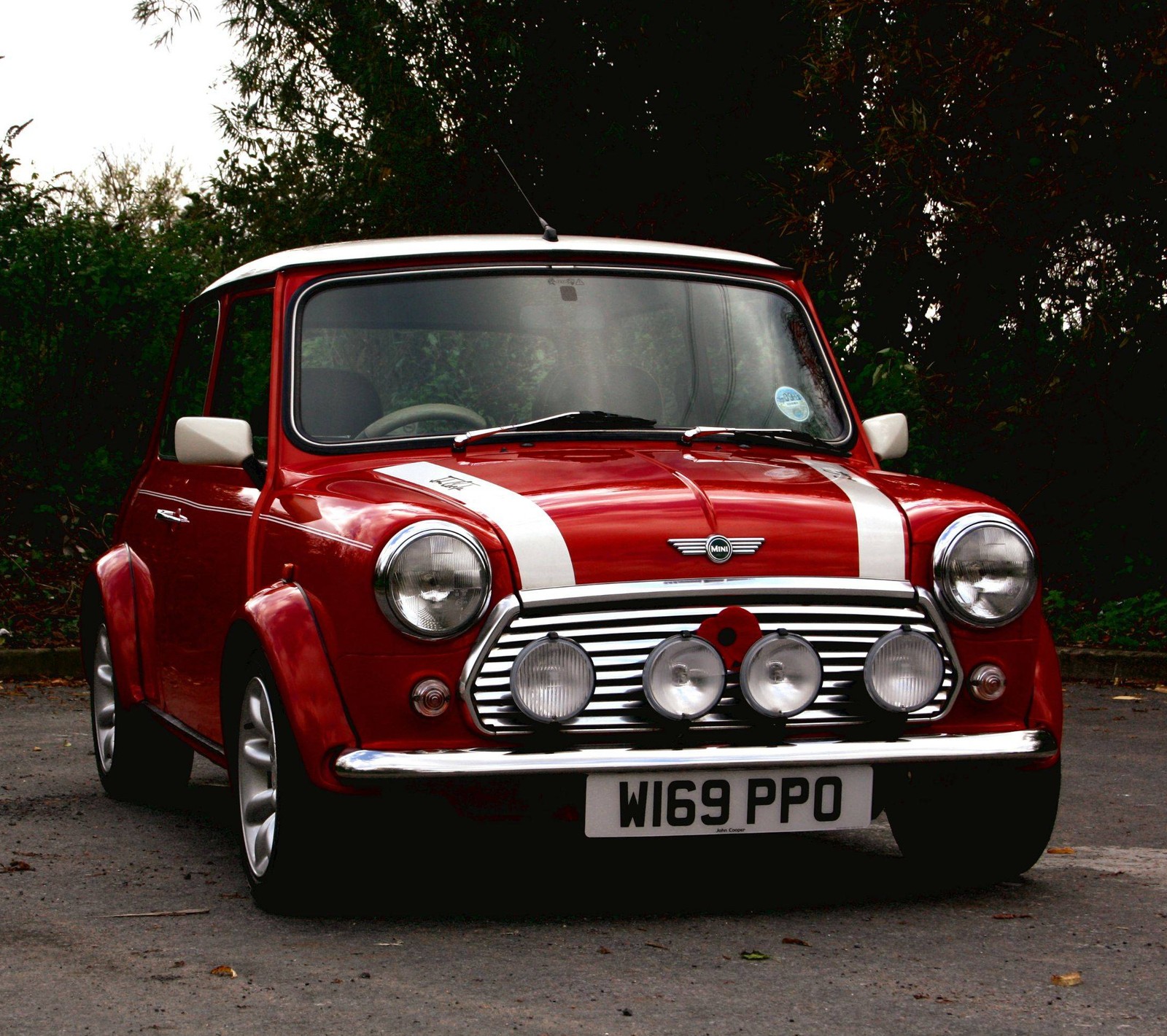 Hay un mini coche rojo y blanco estacionado en un estacionamiento (clásico, mini)