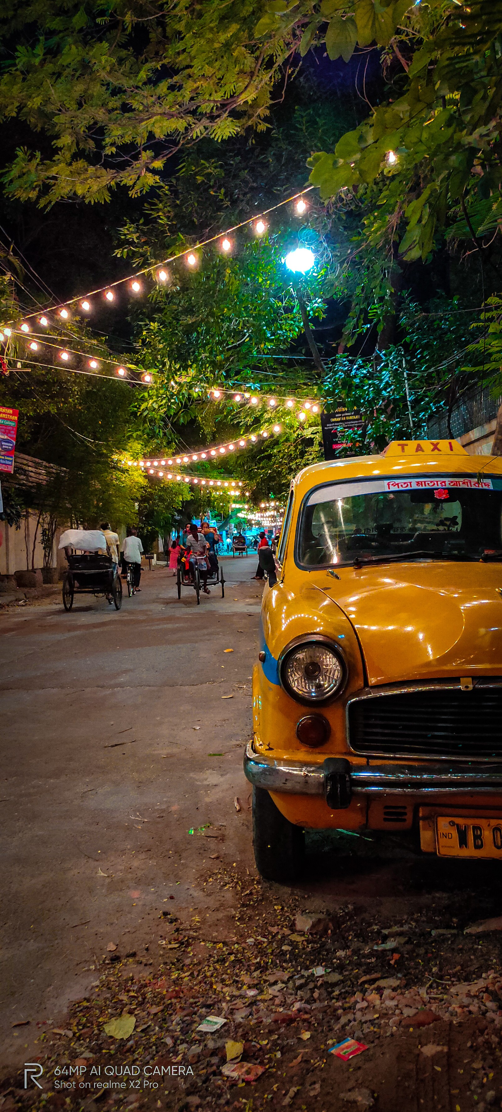 Yellow taxi cab parked on the side of the road with string lights (cars, diwali, durgapuja, kolkata, lights)