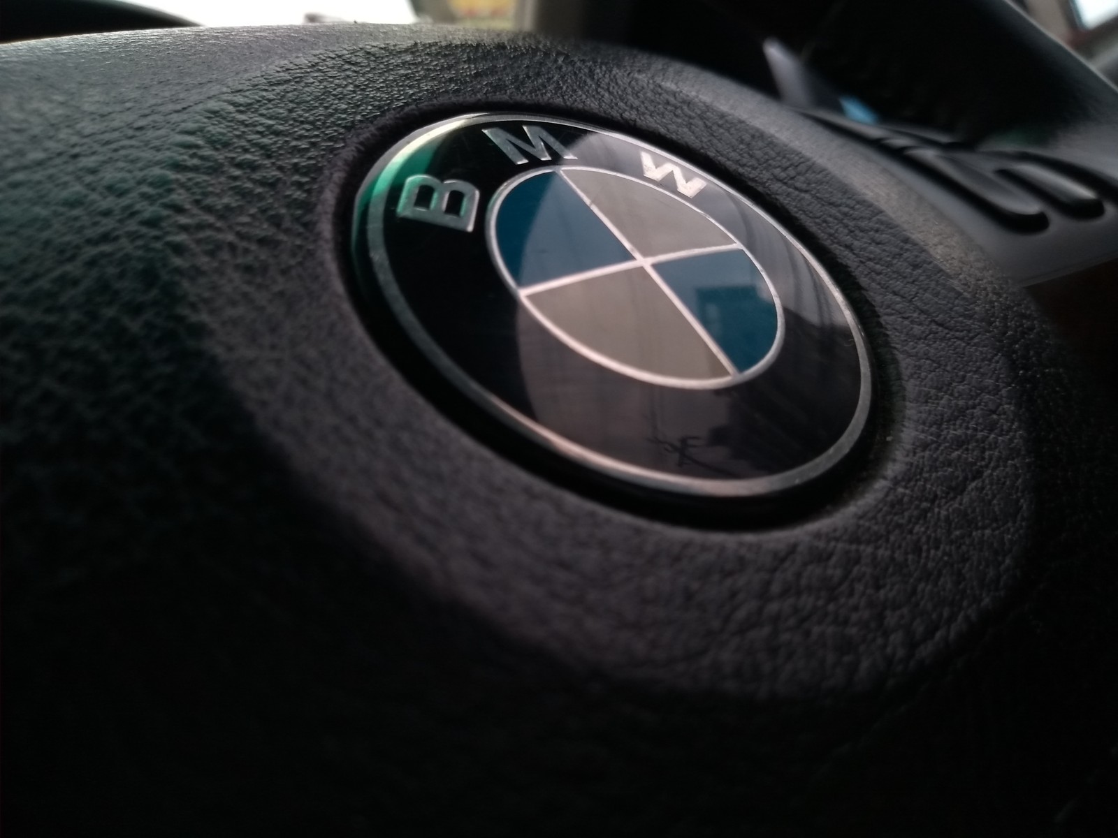 Eine nahaufnahme eines lenkrads mit einem bmw-emblem darauf (innenraum, lenkung, rad)