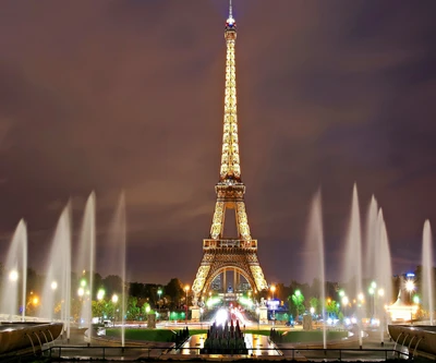 Torre Eiffel iluminada à noite com exibições de fontes em Paris