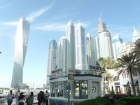 Los modernos rascacielos se elevan contra un cielo azul claro en una bulliciosa metrópoli, mostrando una mezcla de arquitectura comercial y residencial, con palmeras que añaden un toque de verdor.