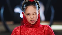 Jennie of BLACKPINK delivers a fierce expression in a striking red outfit, embodying the powerful energy of "Pink Venom.