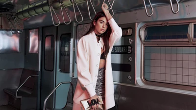 Dua Lipa en un entorno de metro, mostrando un atuendo elegante y una pose impactante.