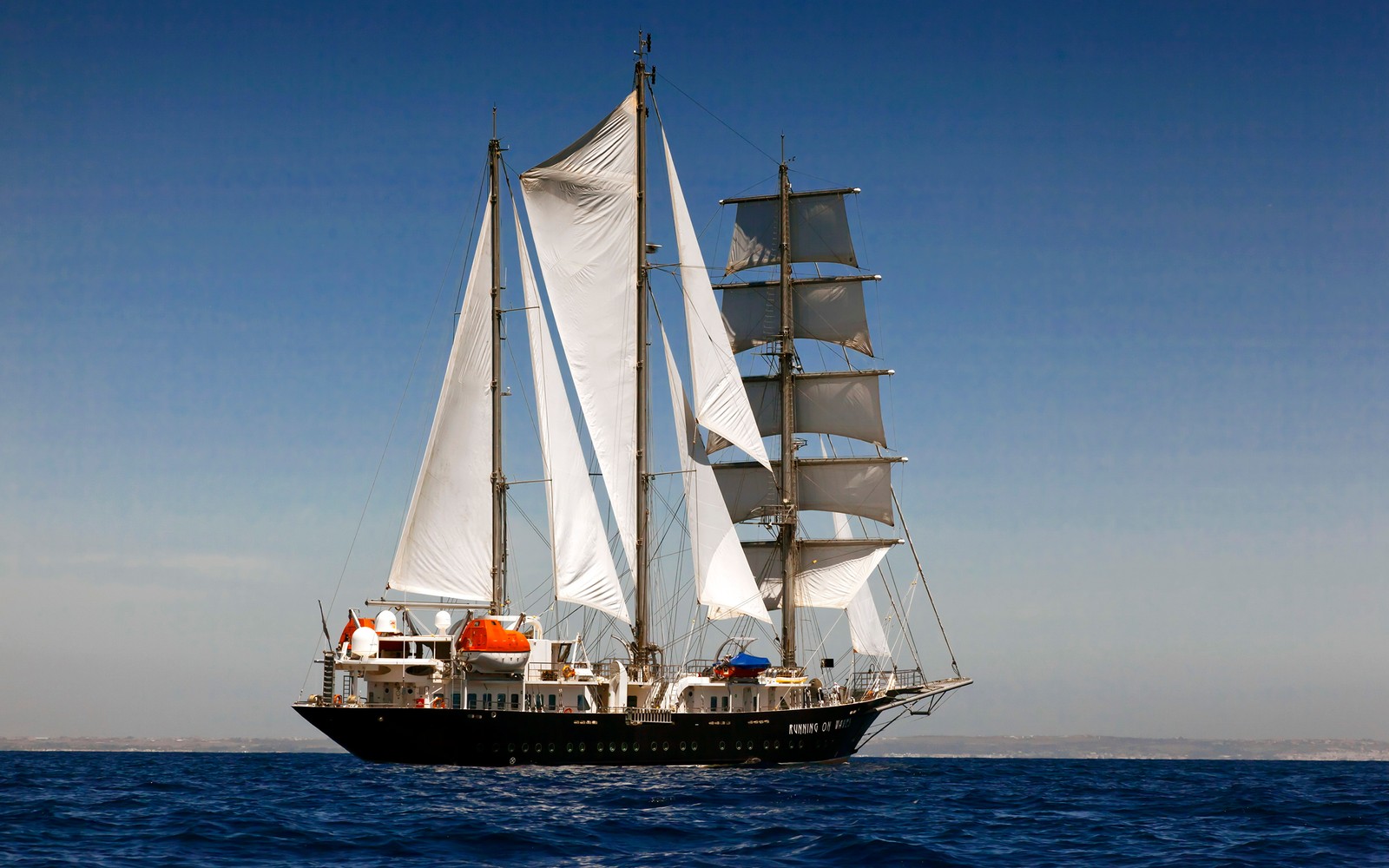 Un voilier fortifié avec des voiles blanches dans l'océan ouvert sous un ciel bleu. (navire, voile, voilier, bateau, transport aquatique)