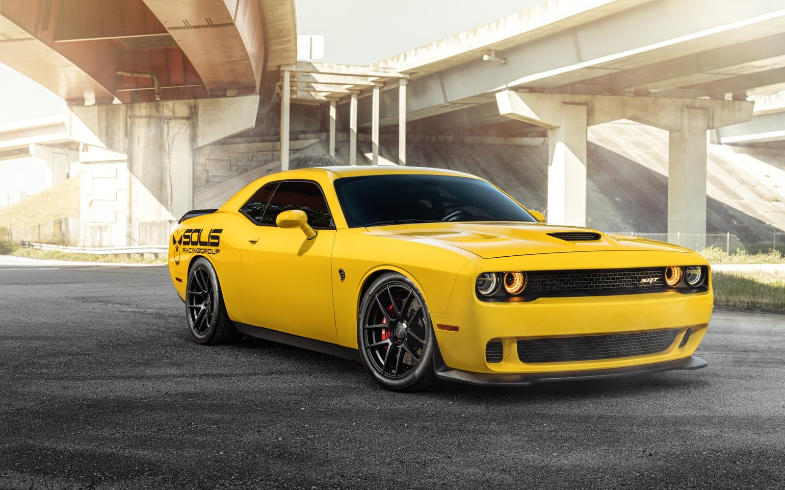 Une dodge challenger jaune est garée devant un pont (dodge, voiture, muscle car, jante, voiture classique)