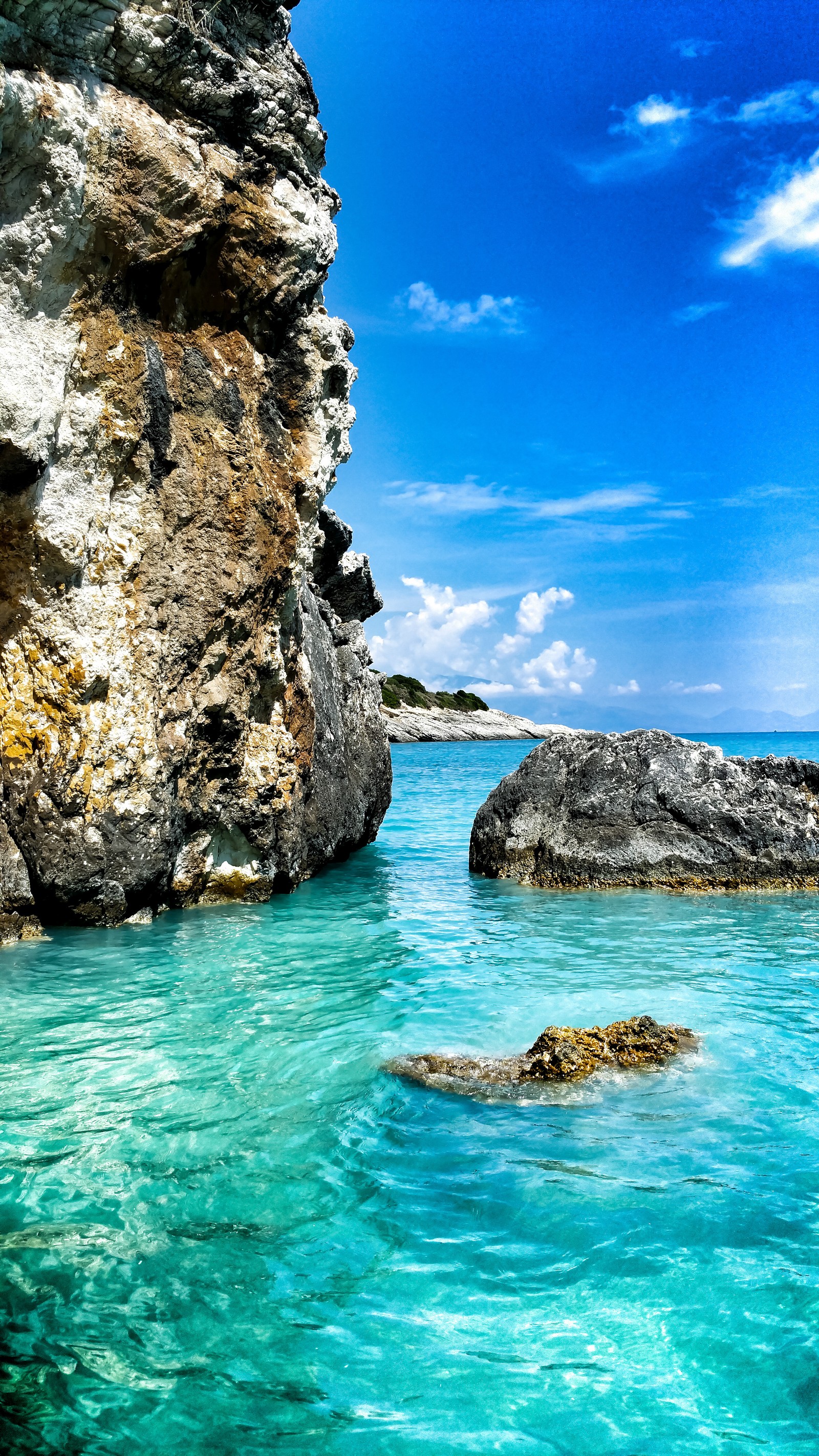 There is a large rock in the water near a large rock (beach, landscape, ocean, paradise, sea)