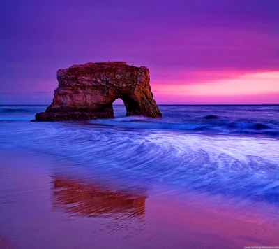 Impresionante atardecer sobre un arco de roca natural en una playa serena