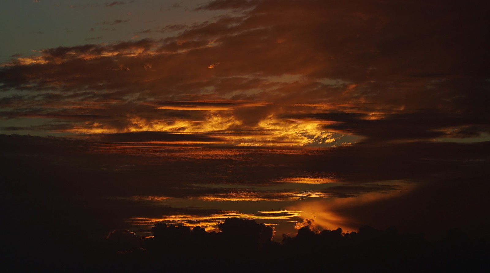 Una vista de un atardecer con algunas nubes y un avión (nube, atardecer, atmósfera, ecorregión, ámbar)