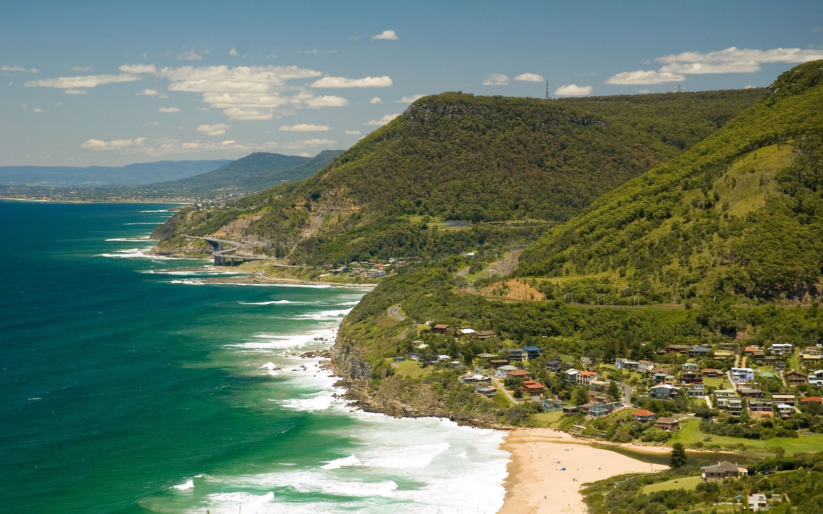 Uma vista de uma praia e uma colina com um corpo de água (mar, praia, costa, promontório, cabo)