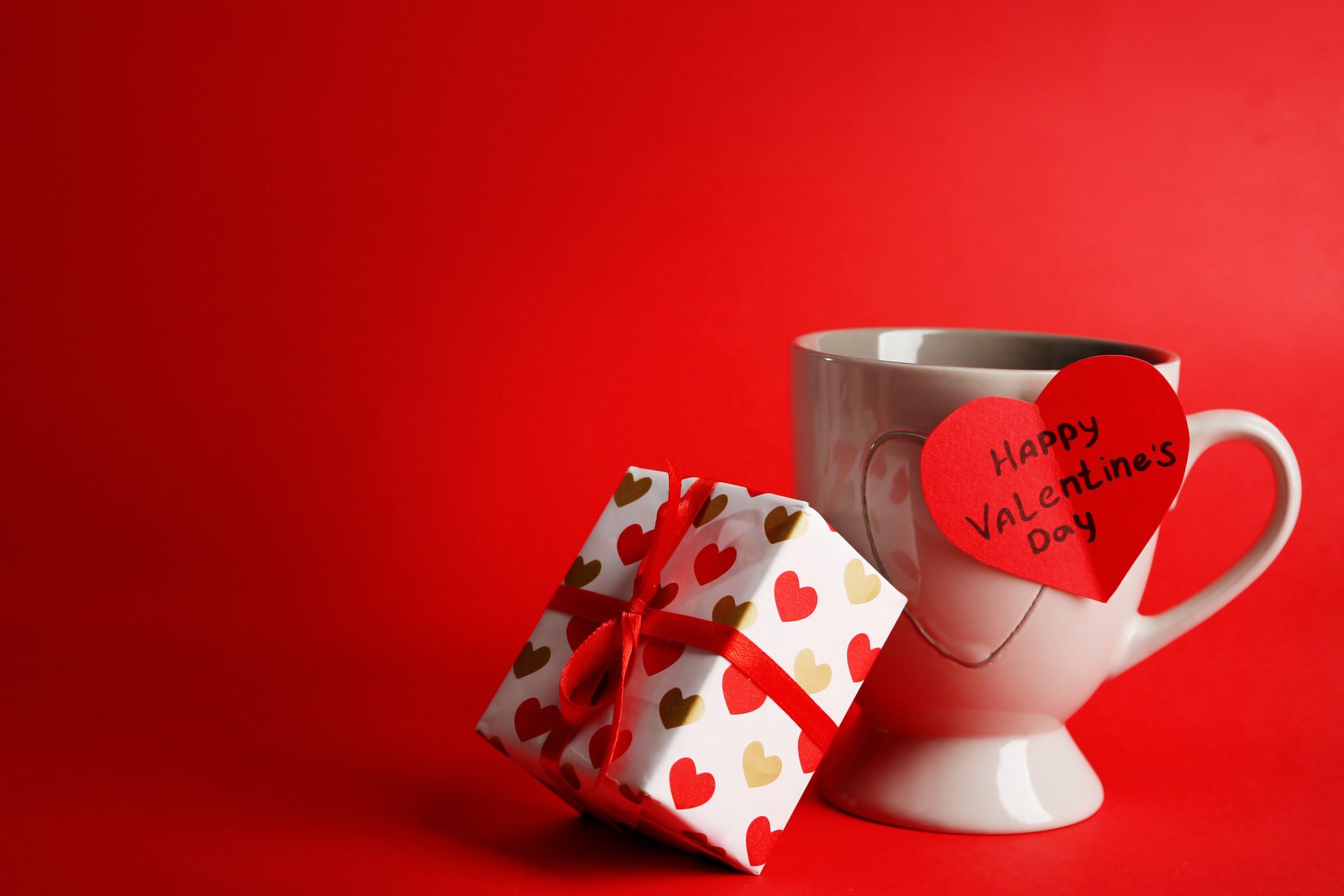 Une tasse avec un cadeau et une carte en forme de cœur dessus (saint valentin, tasse, rouge, tasse à café, vacances)