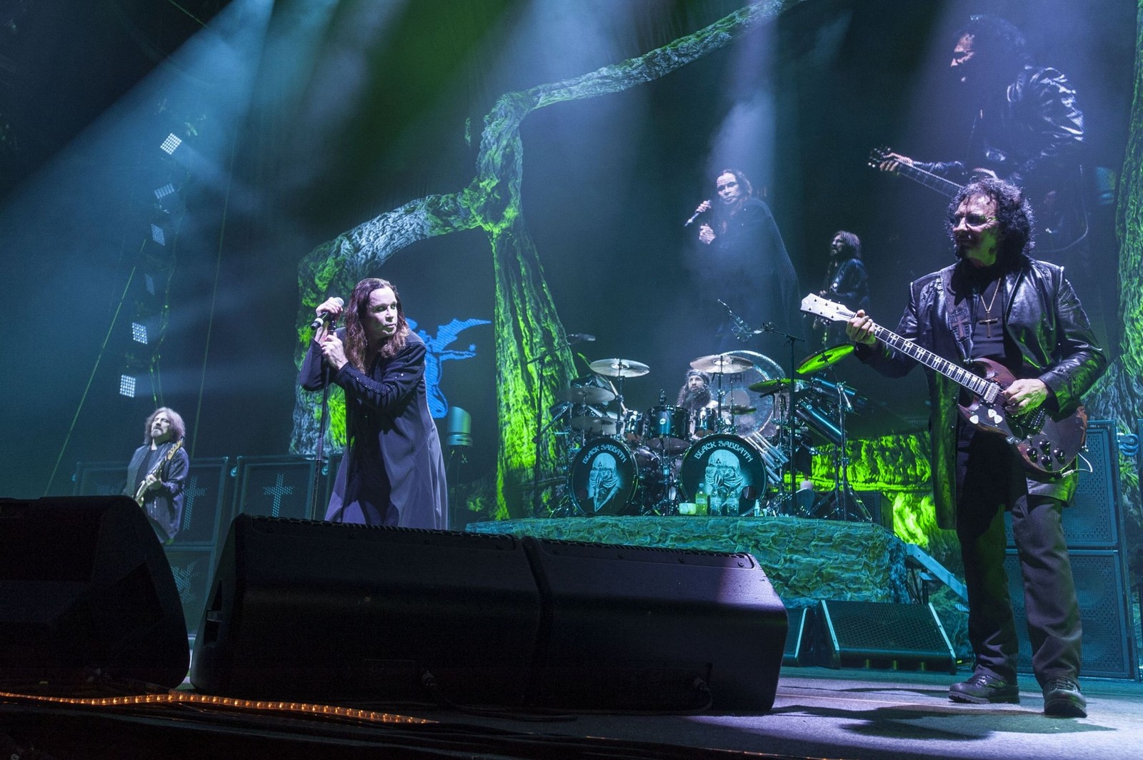 Imagen arafed de una banda actuando en el escenario con un hombre en un traje negro (the end tour, black sabbath, concierto de rock, heavy metal, guitarra)