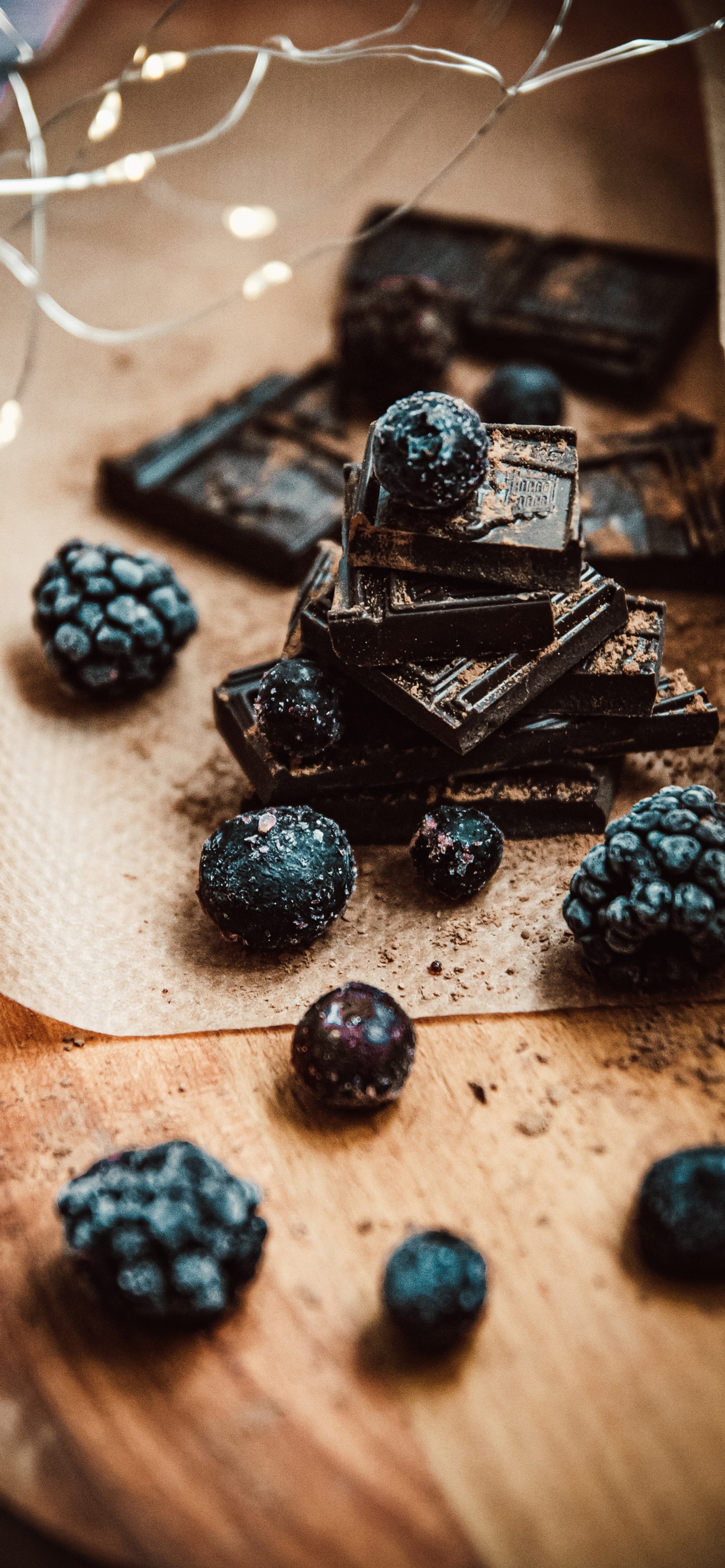 Hay algunas moras y chocolate en una tabla de cortar (chocolate, barra de chocolate, postre, horneado, helado)