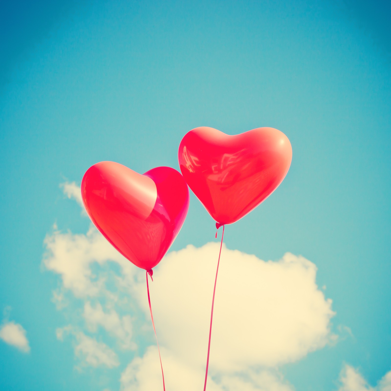 Il y a deux ballons rouges en forme de cœur flottant dans le ciel (ballon, cœur, saint valentin, amour, rouge)