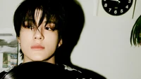 Jeno from NCT Dream captured in a striking portrait with a vinyl record, exuding a cool and contemplative vibe.