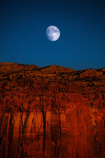 Vollmond beleuchtet die Klippen der Badlands unter einem Dämmerungshimmel