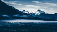 Matin serein dans une chaîne de montagnes majestueuse avec des vallées brumeuses et des sommets enneigés