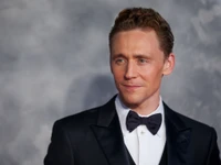 Tom Hiddleston en un esmoquin formal, irradiando elegancia y encanto en un evento de cine.