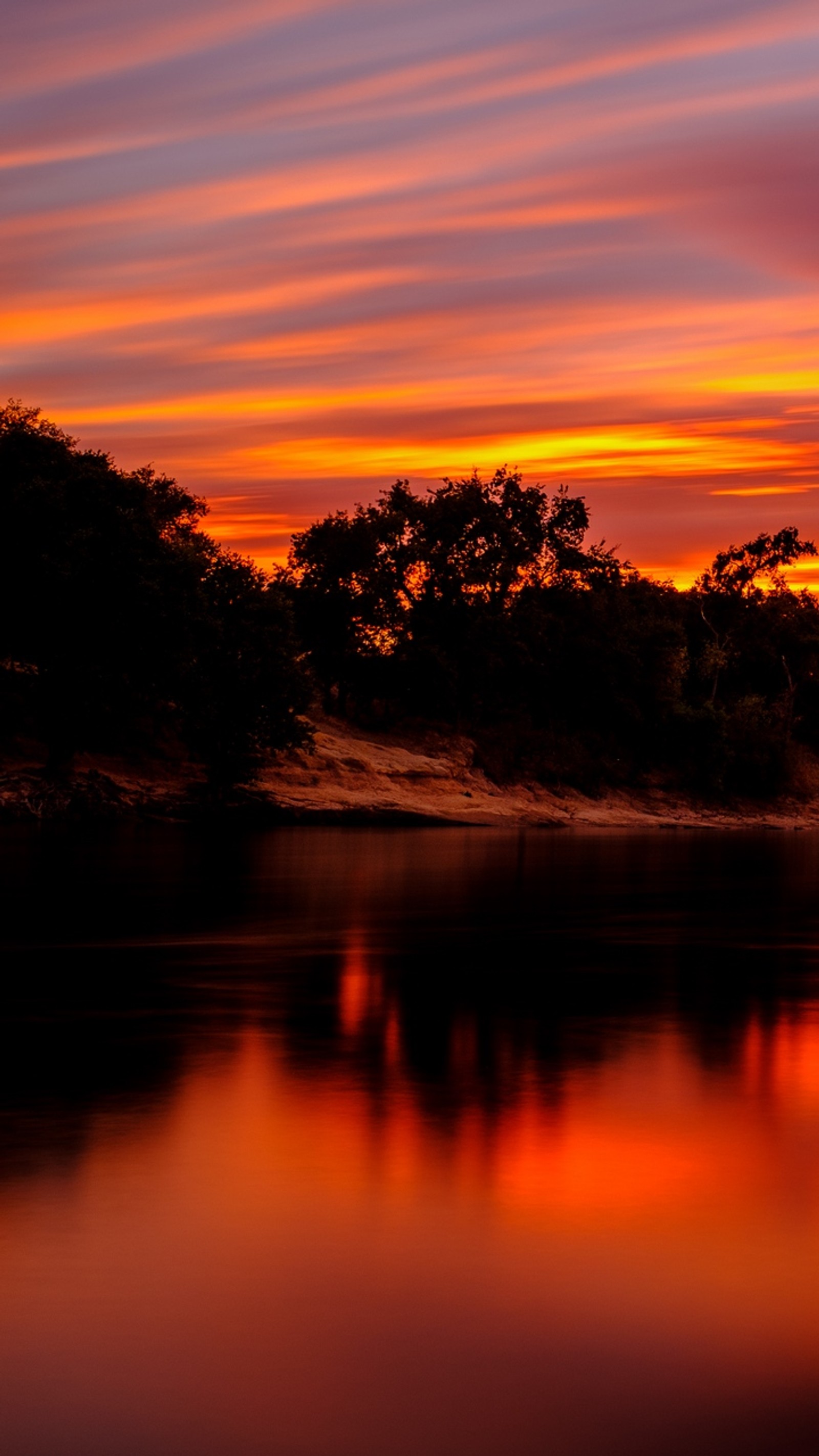 Coucher de soleil sur un plan d'eau avec des arbres et un ciel (coucher de soleil, eau, nuage, ressources en eau, atmosphère)