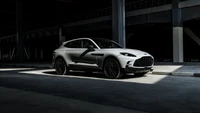 Aston Martin DBX707 в драматическом освещении, демонстрирующий свой элегантный дизайн и роскошные особенности.